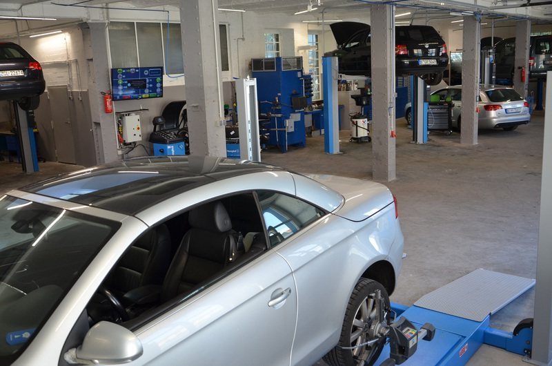 Die Werkstatthalle von Jan's Kfz-Werkstatt mit Fahrzeugen auf blauen Hebebühnen